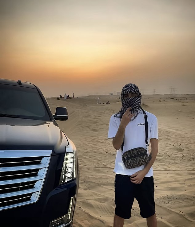A member of Hellbanianz by a jeep in the safari with his face covered by a scarf