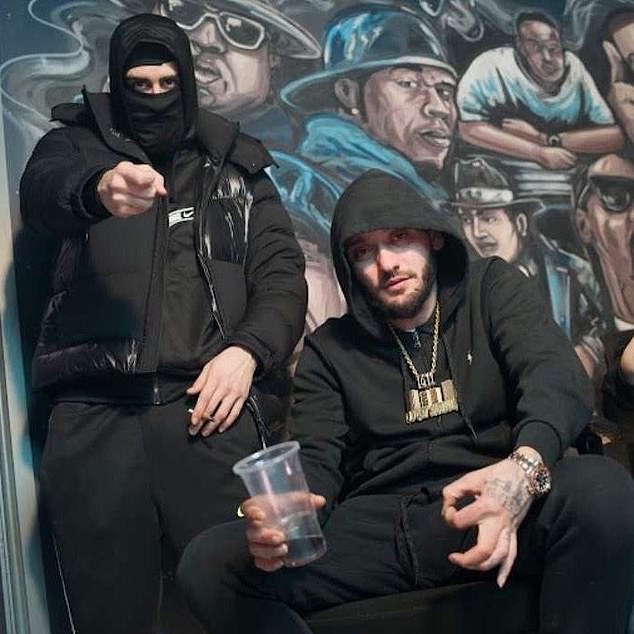 'OneMilli' posed with a masked member. He is wearing a large gold chain which depicts the Gascoigne Estate where the group were based