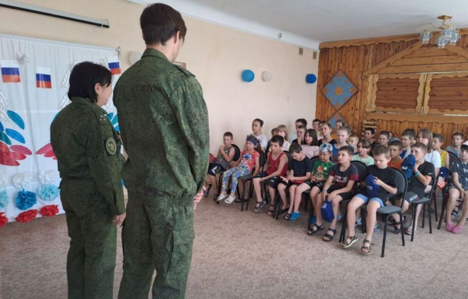 Two Russian soldiers addressing a group of Ukrainian children.