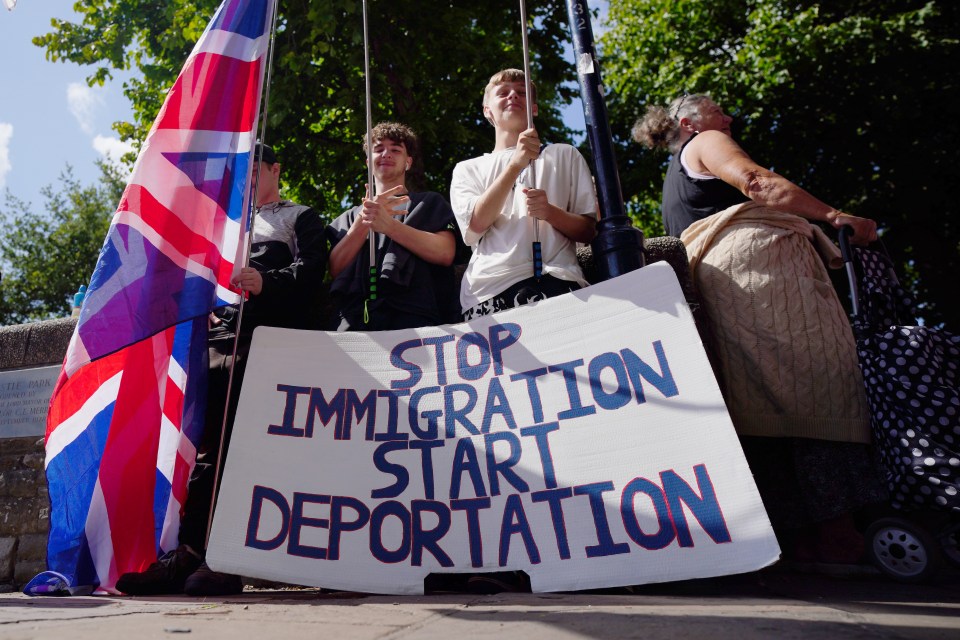 Protestors holding a sign that reads "Stop Immigration Start Deportation".