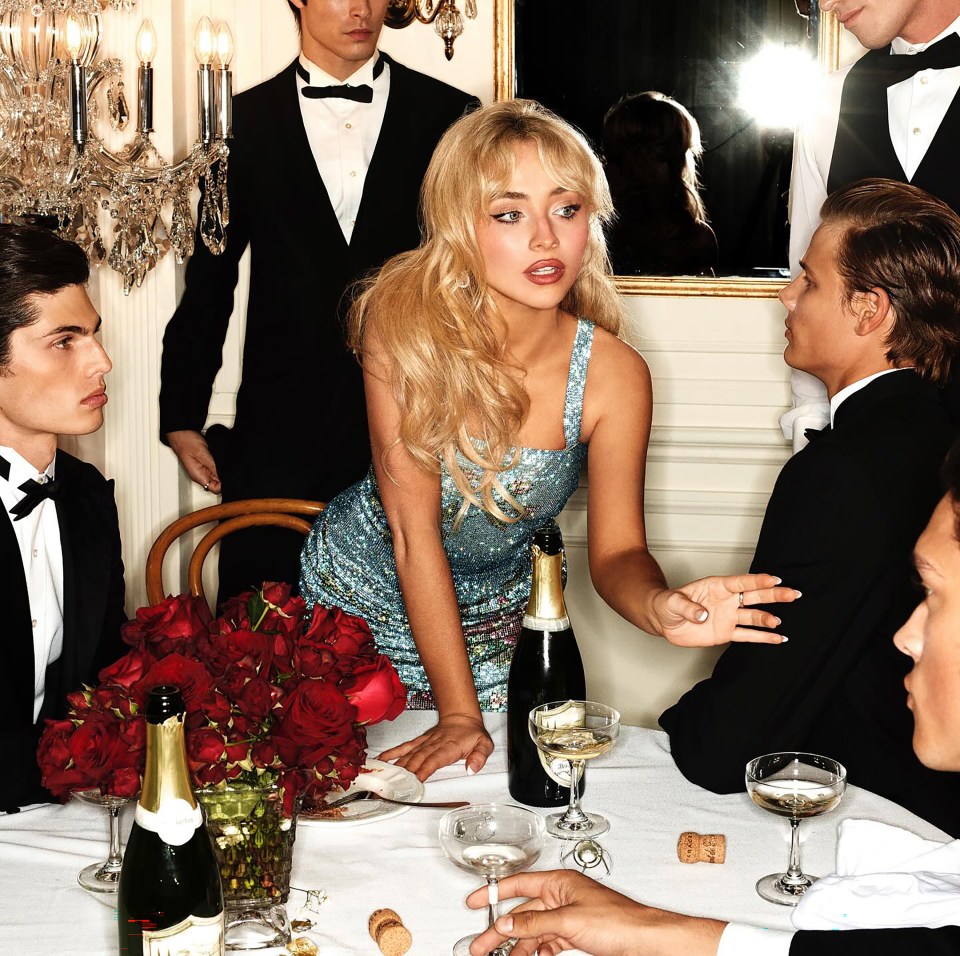 Sabrina Carpenter at a table with men in tuxedos.