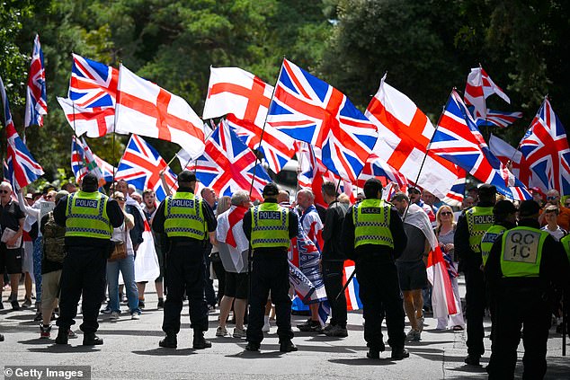 Anti illegal immigration protesters wave Union flags (Union Jacks) as police hold the line outside The Roundhouse hotel, on August 09, 2025 in Bournemouth