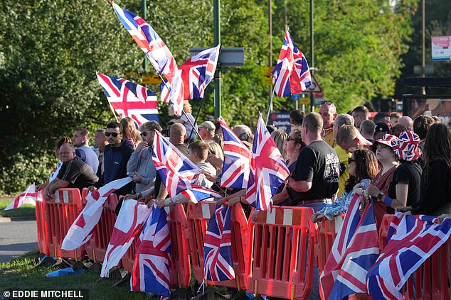 Protesters wave Union Jack flags behind barricades outside the Park Hotel in Chichester on Friday
