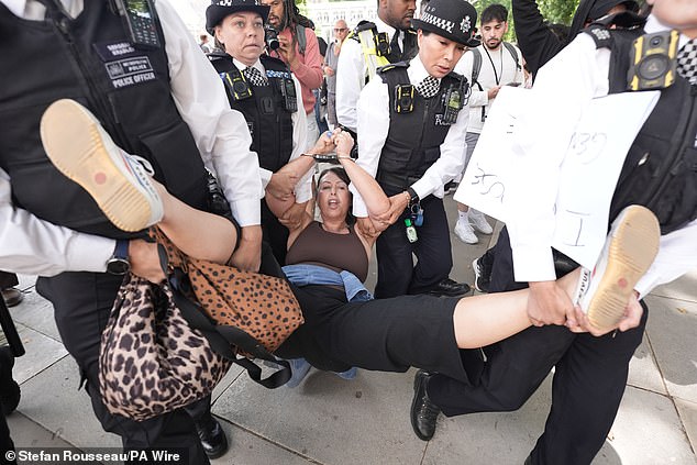 A woman is led away by police officers as supporters of Palestine Action take part in a mass action in Parliament Square