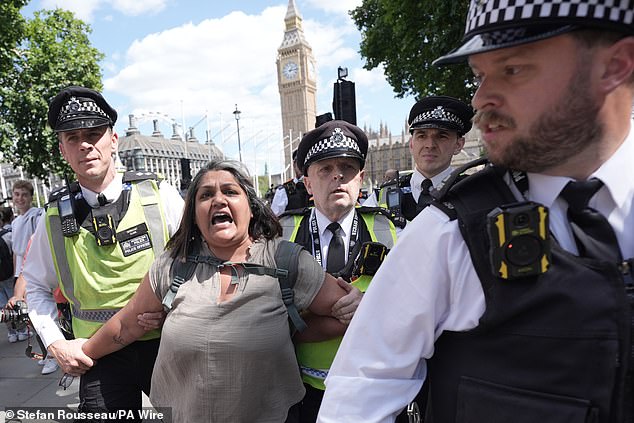 A woman is led away by police officers as supporters of Palestine Action take part in a mass action in Parliament Square