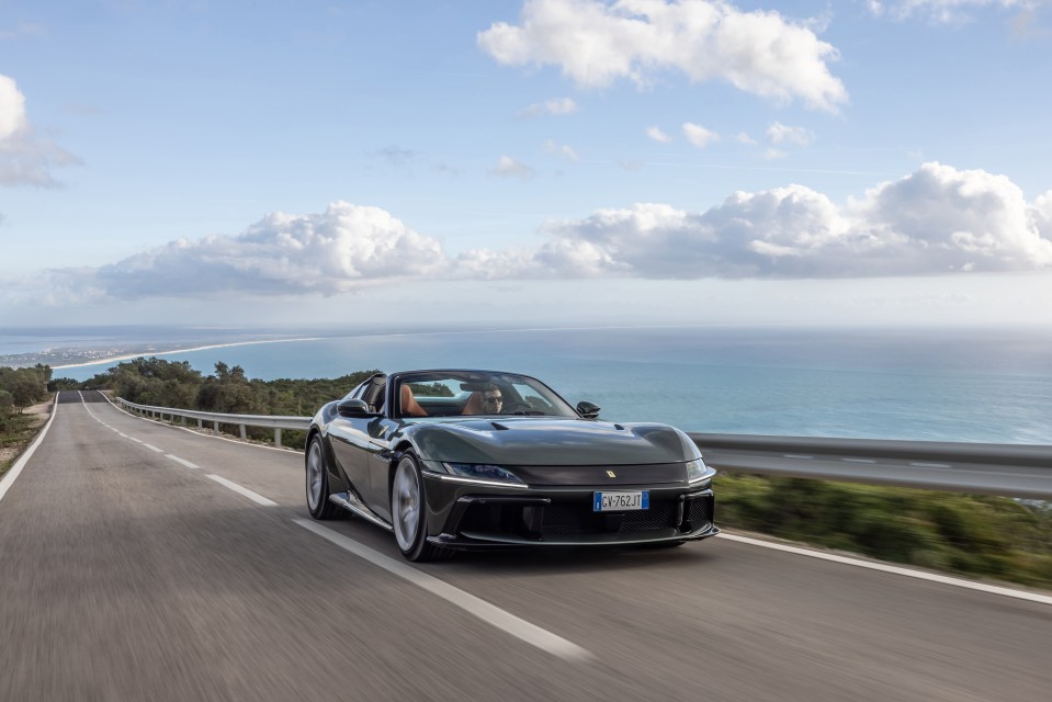 A green Ferrari driving on a coastal road.