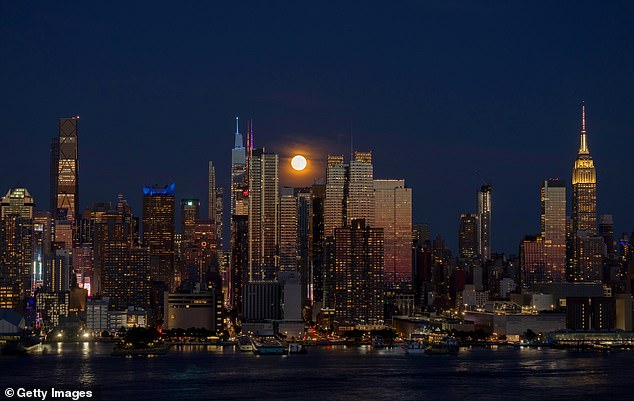 The last full moon of summer is caught rising between two Manhattan skyscrapers in New York City