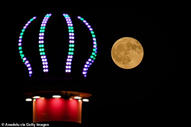 The full moon rises behind a Ferris wheel in Mosul, Iraq