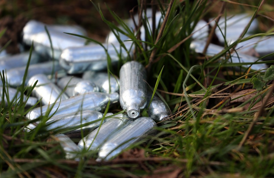Discarded nitrous oxide canisters in grass.