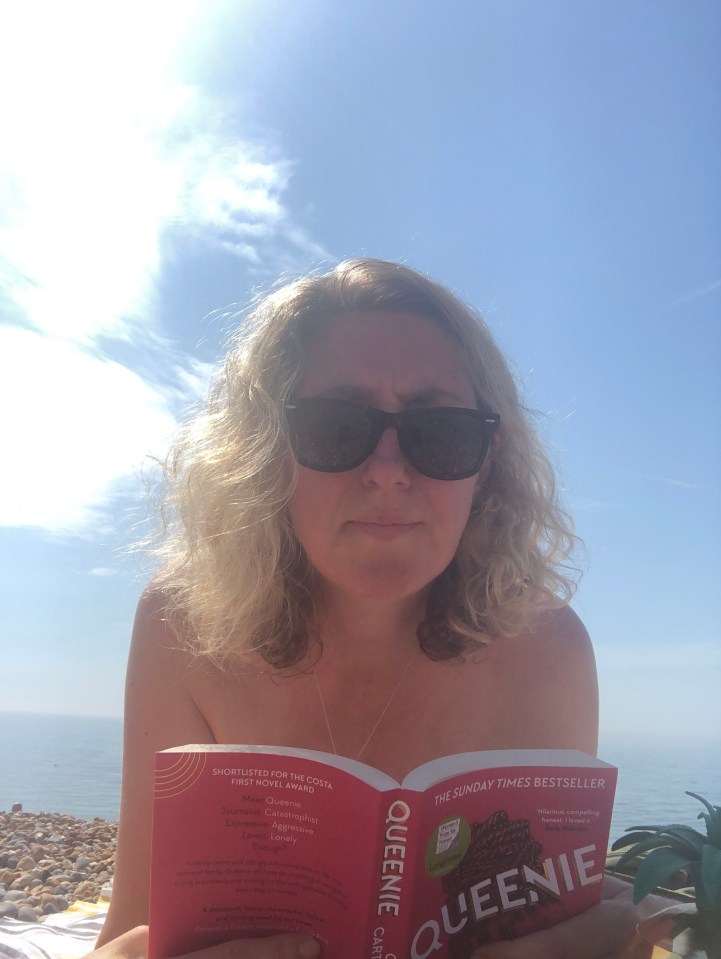 Woman reading "Queenie" at the beach.