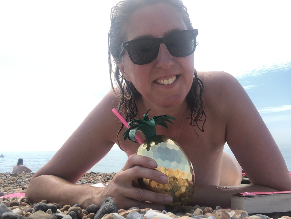 Woman on a beach holding a pineapple-shaped cocktail.