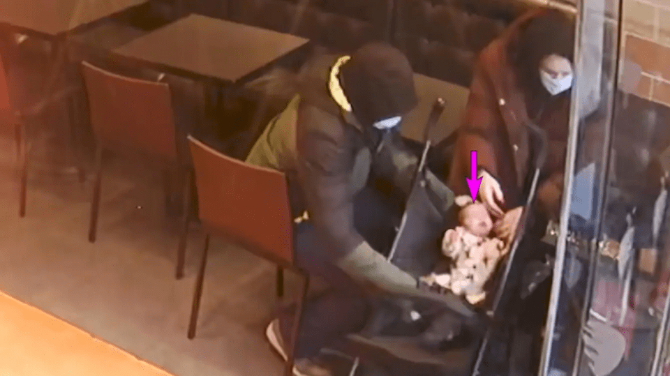Surveillance image of a couple with a baby in a stroller at a cafe.