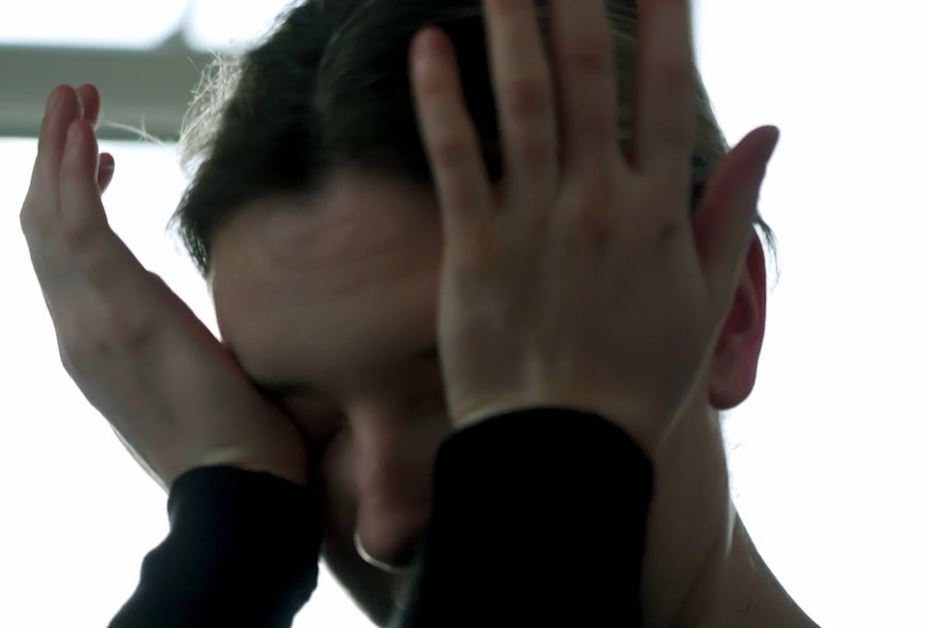 A pregnant woman covering her face with her hands.