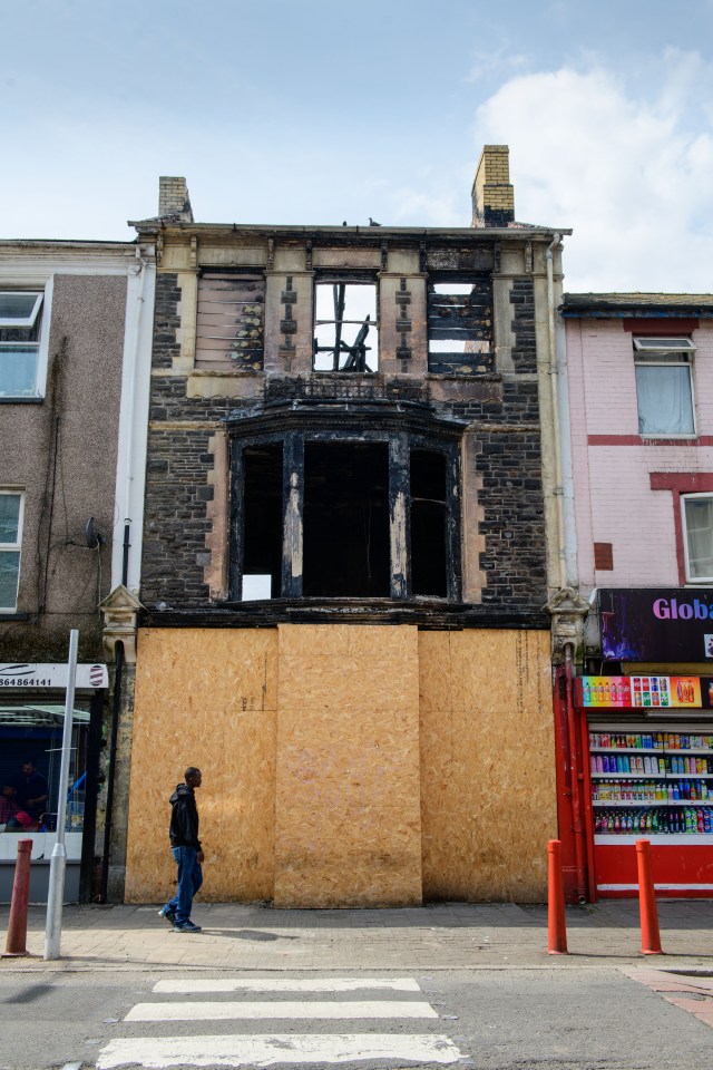 Burned-out building boarded up on a city street.