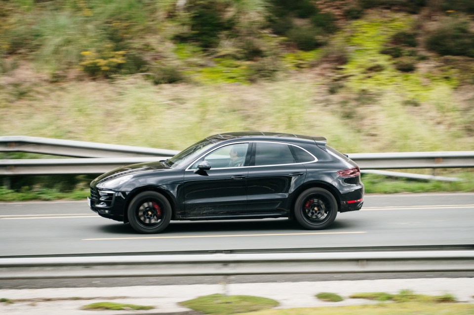 Black Porsche Macan driving on a highway.