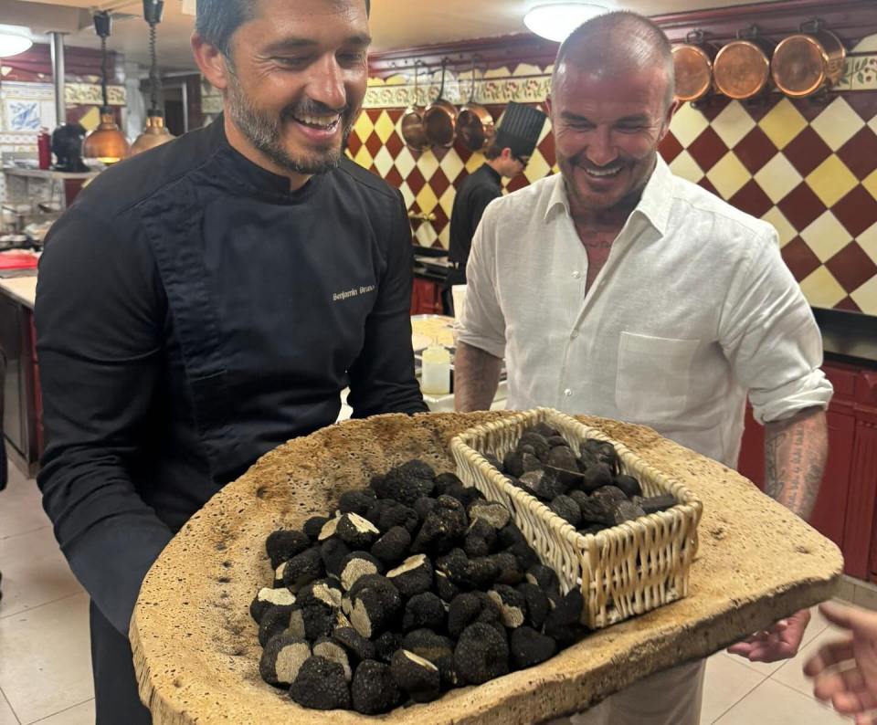 David and Cruz Beckham with a chef holding a large platter of truffles.