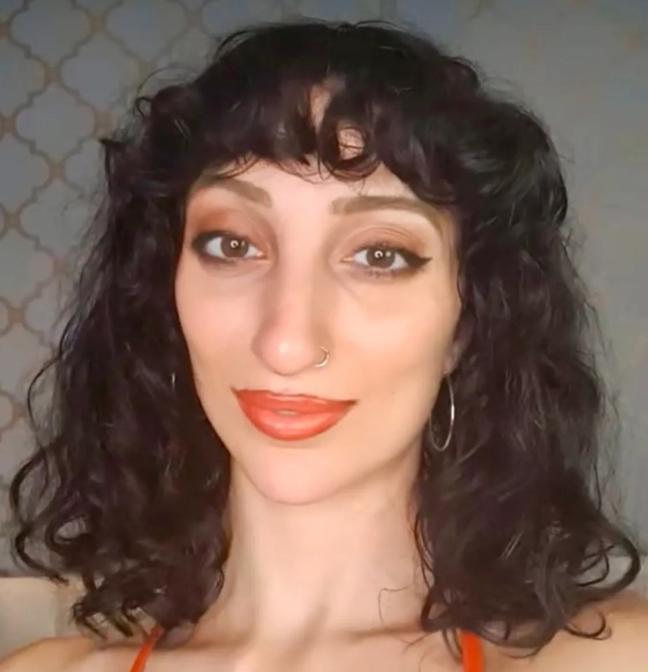 Headshot of a woman with dark curly hair and makeup.