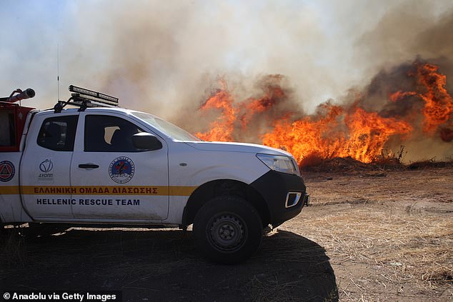 Flames and smoke rise from burning trees while firefighters continue their efforts to extinguish the fire that broke out in the forest area near the Komotini, Greece on August 10, 2025