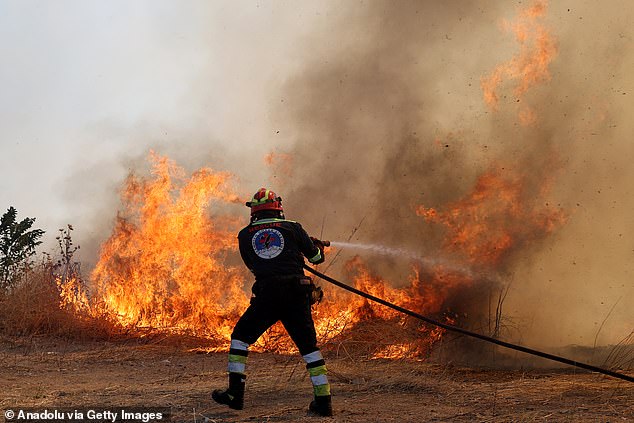 lames and smoke rise from burning trees while firefighters continue their efforts to extinguish the fire that broke out in the forest area near the Komotini, Greece on August 10, 2025