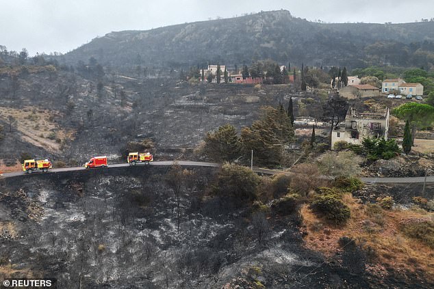 A drone view shows fire trucks driving past a house severely damaged by fire in Jonquieres, near Narbonne, southern France, as wildfires sweep through the region, August 8, 2025