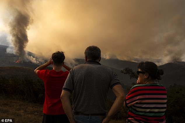 Residents watch as smoke rises from a fire that broke out late the previous day in the surroundings of Maceda in Galicia, northwestern Spain, 10 August 2025