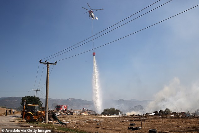 A helicopter drops water to put out the fire while firefighters continue their efforts to extinguish the fire that broke out in the forest area near the Komotini, Greece on August 10, 2025