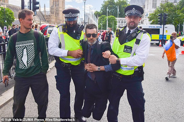 Hundreds of pro-Palestine campaigners descended on London's Parliament Square on Saturday, with hundreds of people arrested (pictured: police lead a protester away)