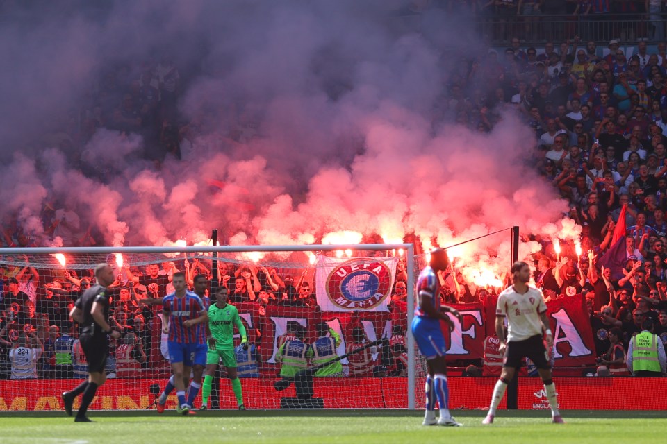 Crystal Palace fans lighting flares and smoke bombs during a soccer match.