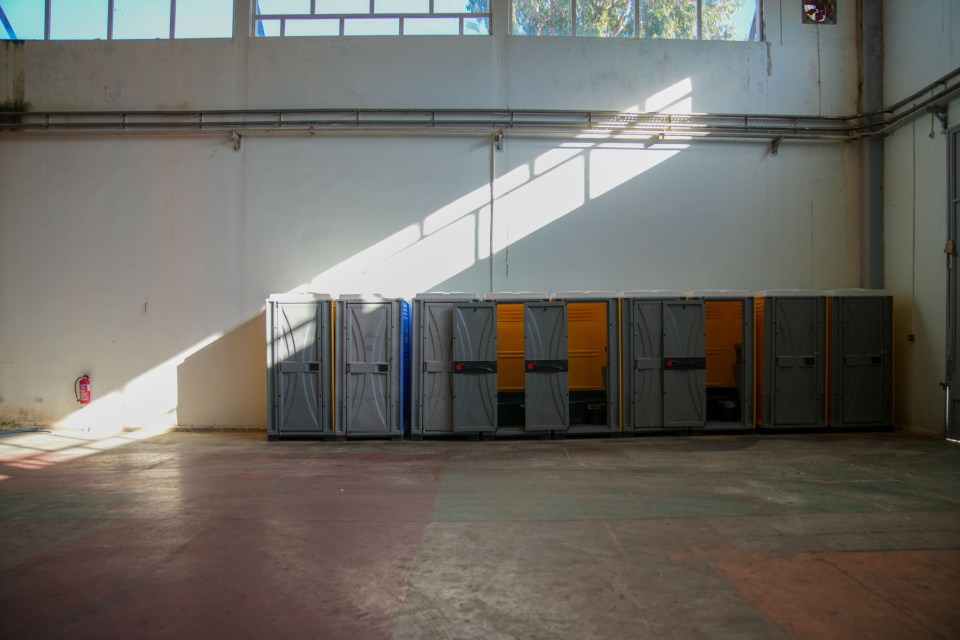 Portable toilets in an empty exhibition hall.