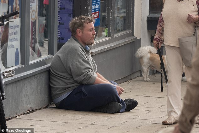 People were sat outside empty shops and grocery stores when the Daily Mail visited on Tuesday