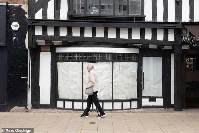 A woman walks past yet another boarded up building. It is the Mercure Shakespeare Hostel