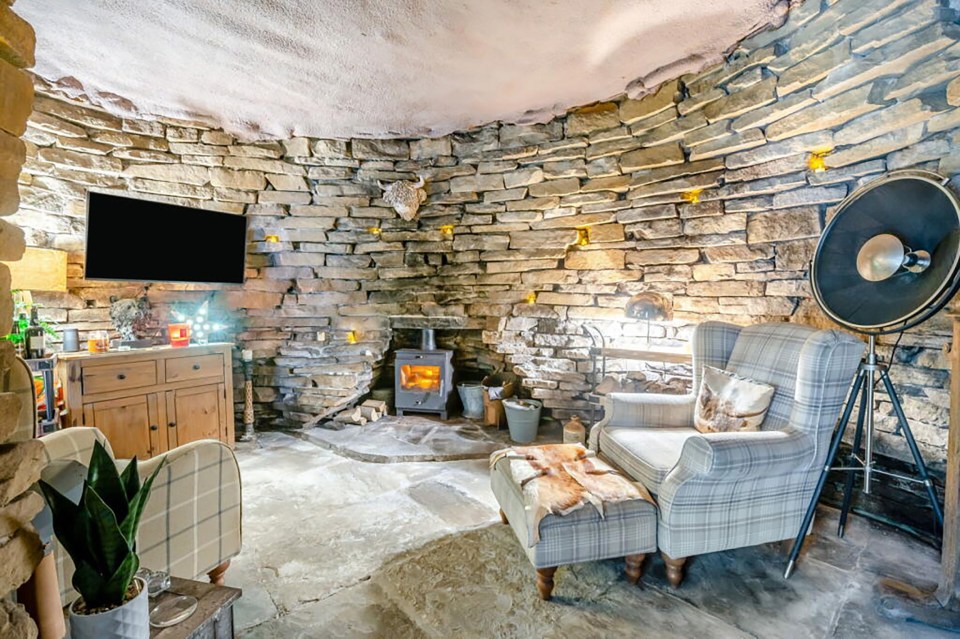 Interior of a stone-walled living room with a wood-burning stove.