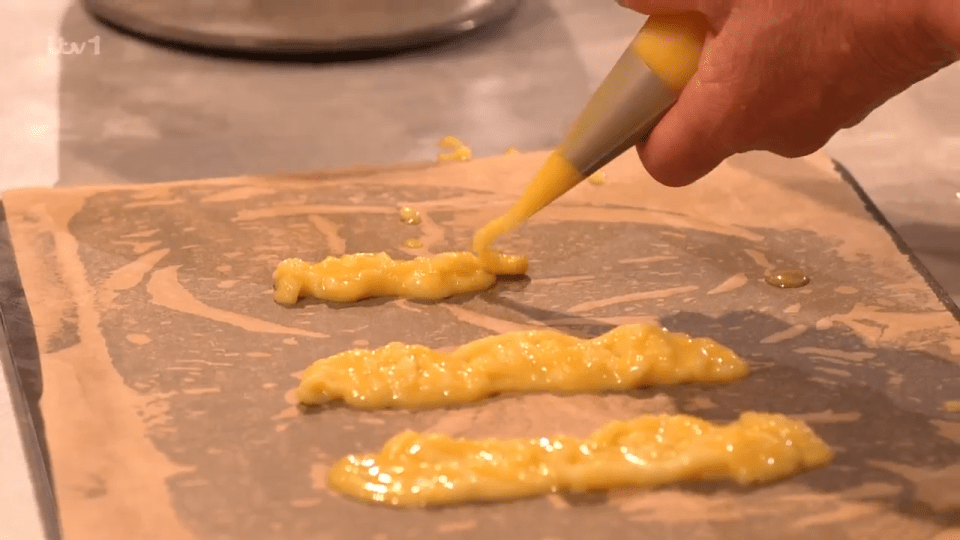 Piping yellow batter onto baking paper.