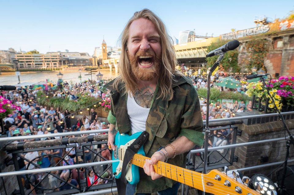 Sam Ryder performing on stage at an outdoor concert.