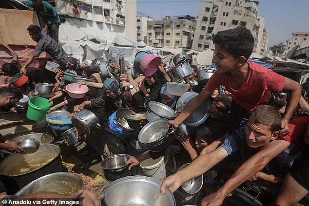 Starving Palestinians including women and children holding pots wait to receive food distributed by a charity organization as Israel continue to block humanitarian aid from reaching the Gaza Strip on August 10, 2025