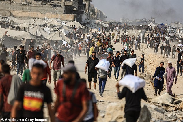 Palestinians struggling with hunger flock to an aid distribution point near the Zikim Crossing to receive limited supplies of flour and other food items, in northwestern Gaza on August 10, 2025