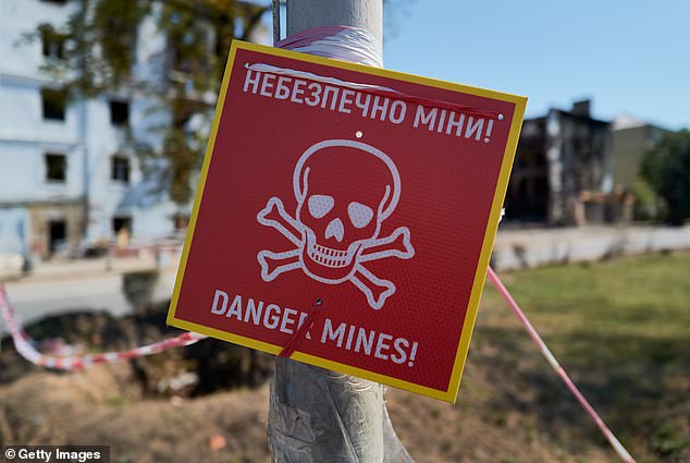A sign warns of mine danger outside residential buildings bombed by Russian forces on August 10