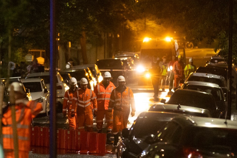 Workers in orange vests at night time flood scene.