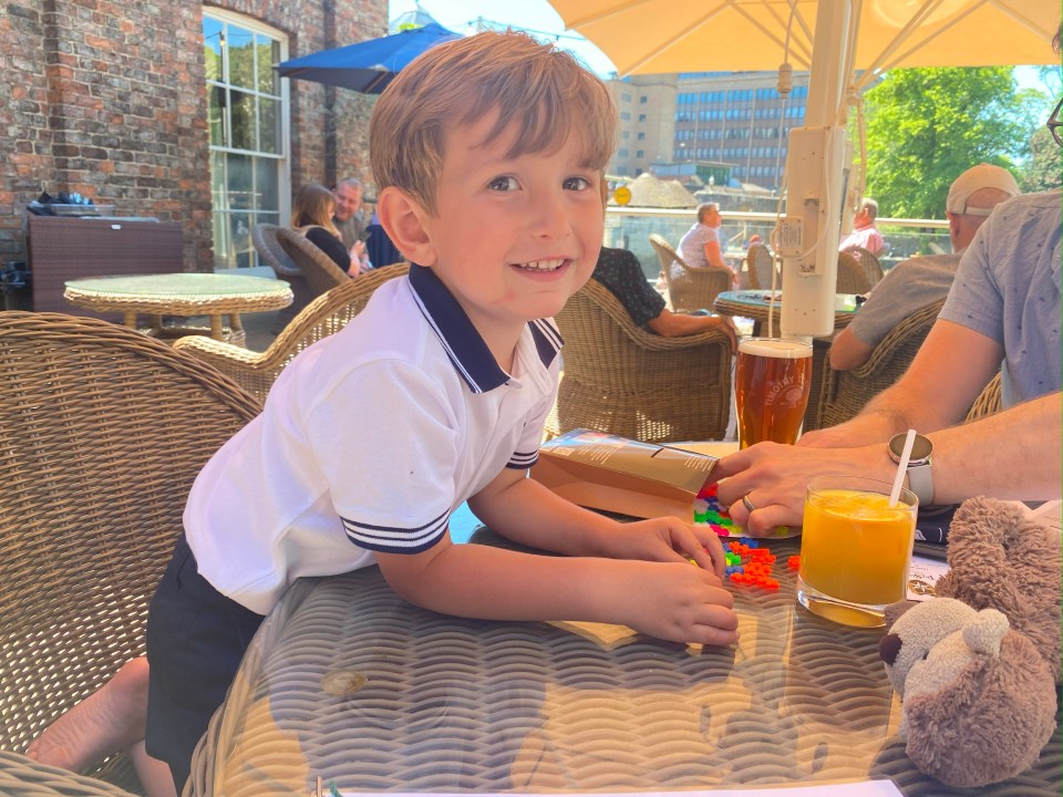 Young boy playing with colorful blocks at an outdoor cafe.