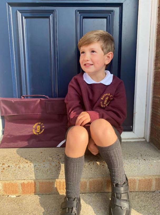 Boy in school uniform sitting on steps with school bag.