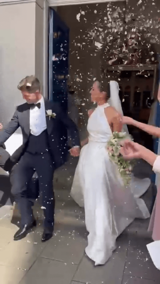 Bride and groom exiting a building, showered with confetti.