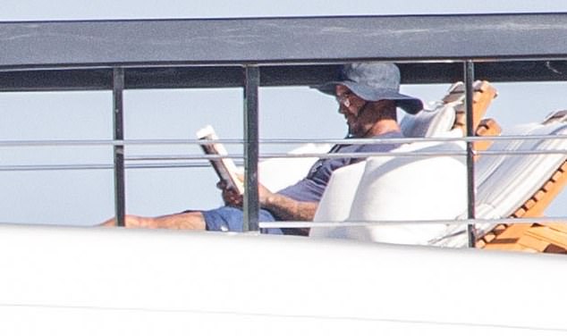 David later donned a t-shirt over his tattooed and muscular physique and joined his wife by pulling on a sun hat and enjoying his book