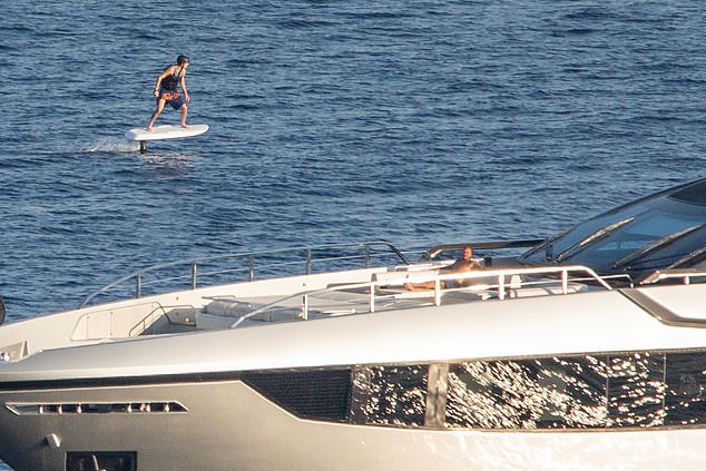 Meanwhile son Cruz (L) took to the water on an electric surf board