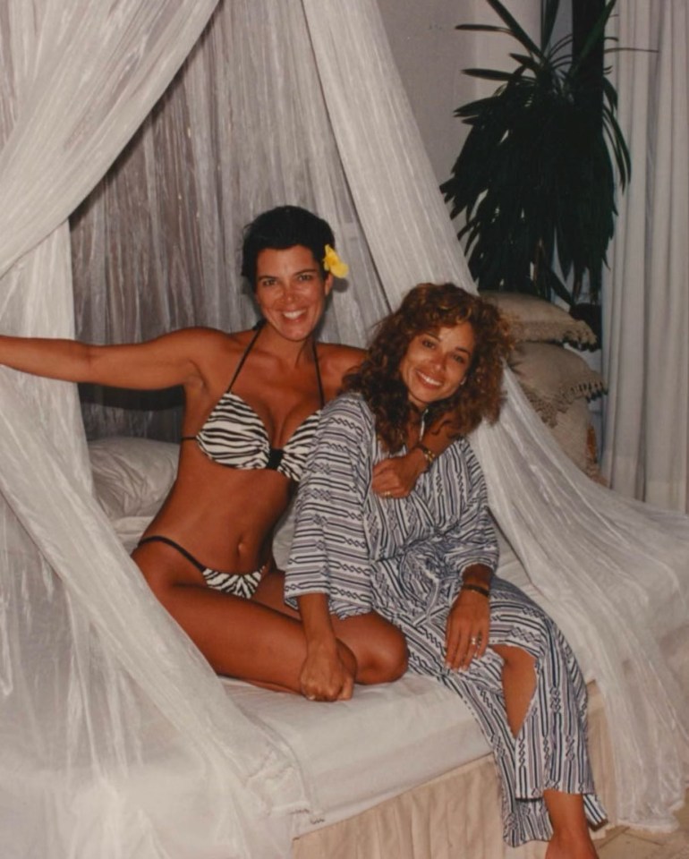 Kris Jenner and a friend on a bed, under a canopy.