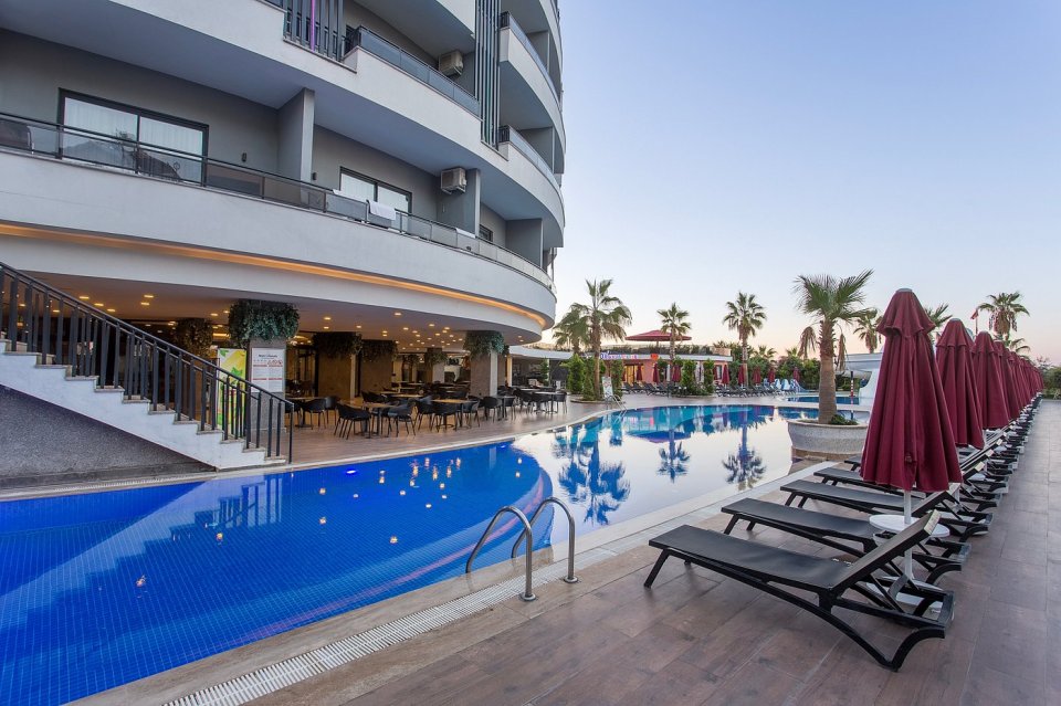 Hotel pool and patio area with lounge chairs and umbrellas.