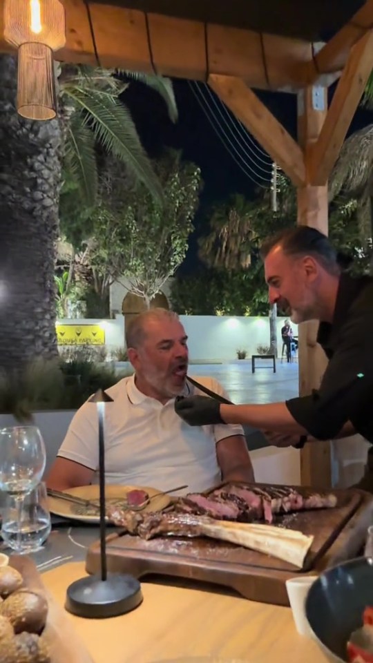Ange Postecoglou having a large steak cut for him at a restaurant.