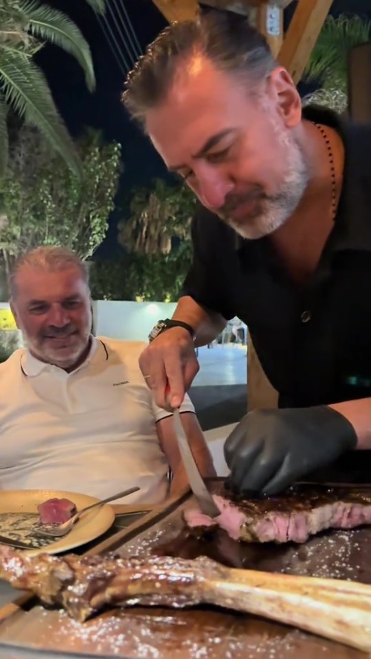 A man carving a large steak for another man.