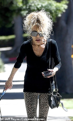She looked stylish in a black top, leopard leggings, dangling cross earrings, and designer sunglasses