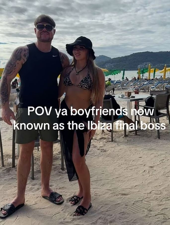 Photo of a couple on a beach; the man is wearing a black tank top and shorts, and the woman is wearing a leopard-print bikini top and a black sarong.  Text overlay reads "POV ya boyfriends now known as the Ibiza final boss".