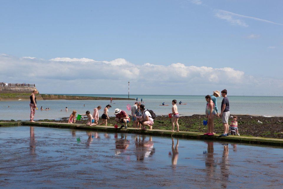 Families enjoying a beach day despite windy conditions.